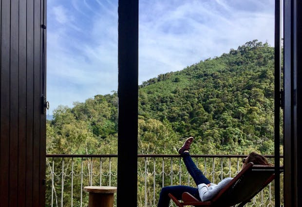 Woman enjoying a serene moment on a balcony overlooking lush Brazilian mountains.